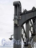Большеохтинский мост («Петра Великого»). Улиткообразный держатель с подвешенным к нему удлиненным плоским многогранным фонарем. Фото июль 2009 г.
